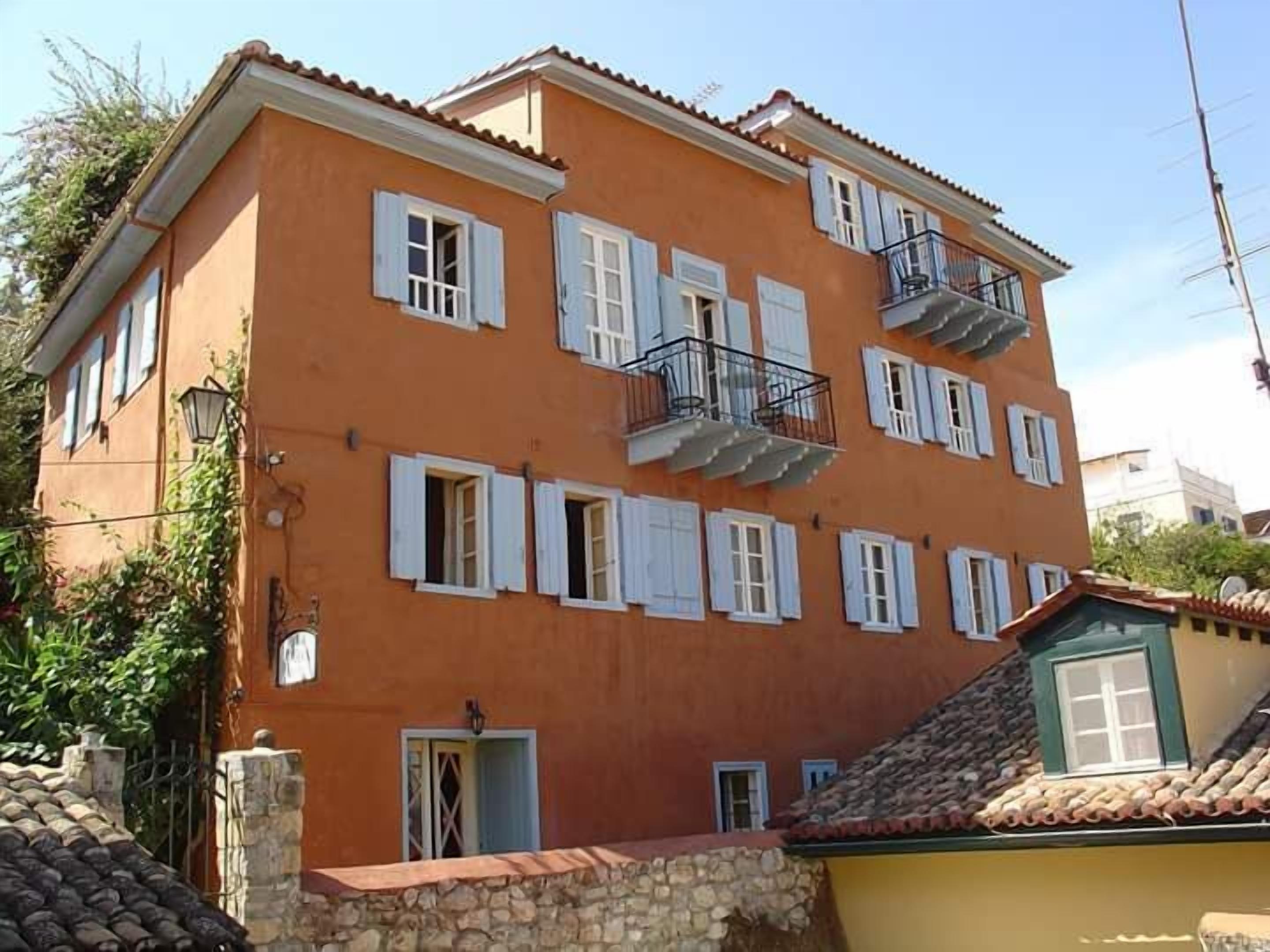 A multi-story building with a red facade, white shutters, and balconies.