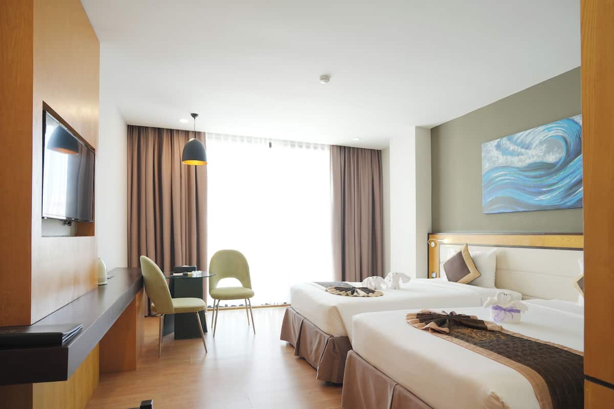 A hotel room with a bed, a desk, a chair, and a television.