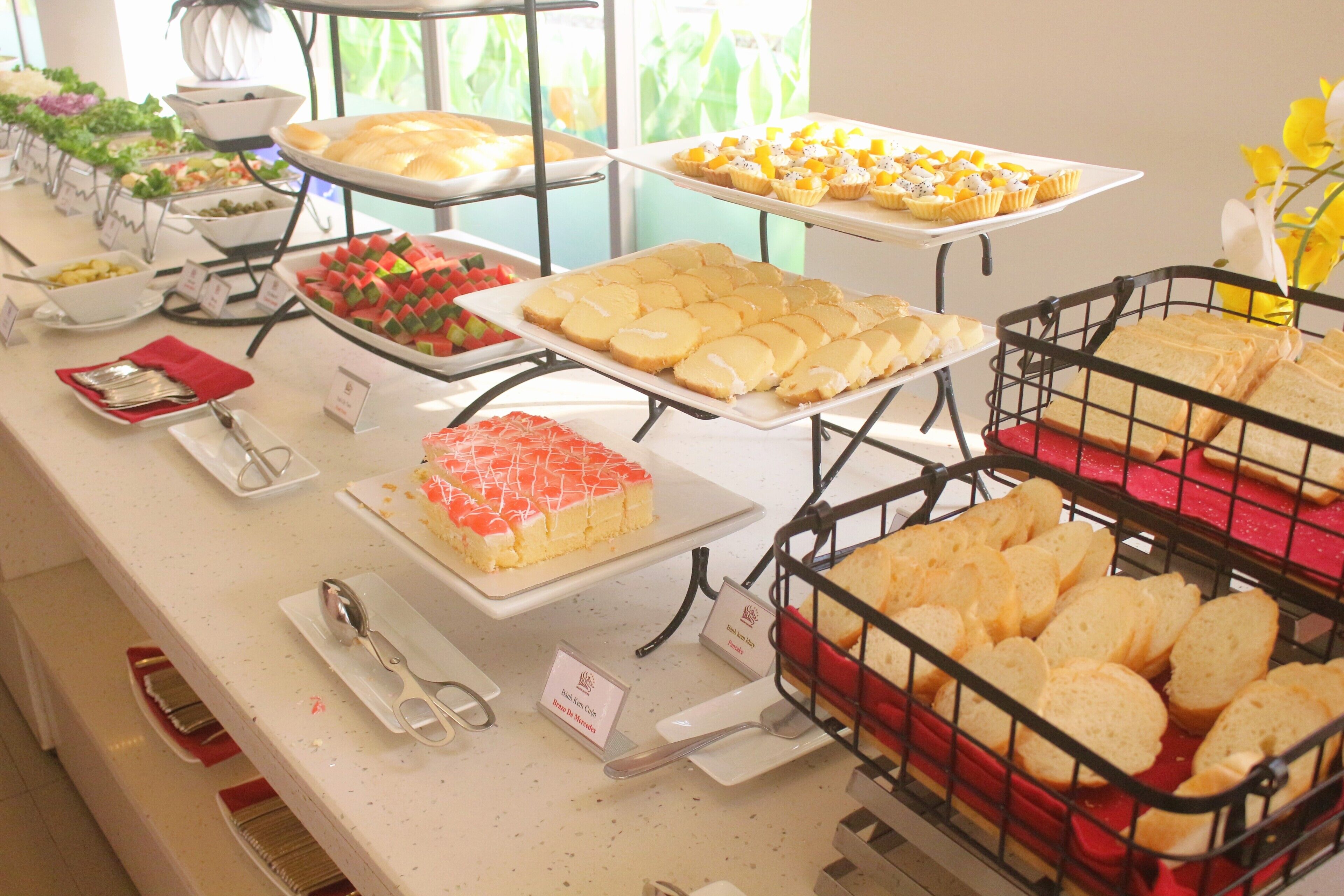 A buffet with various food items, including cakes, pastries, and bread.