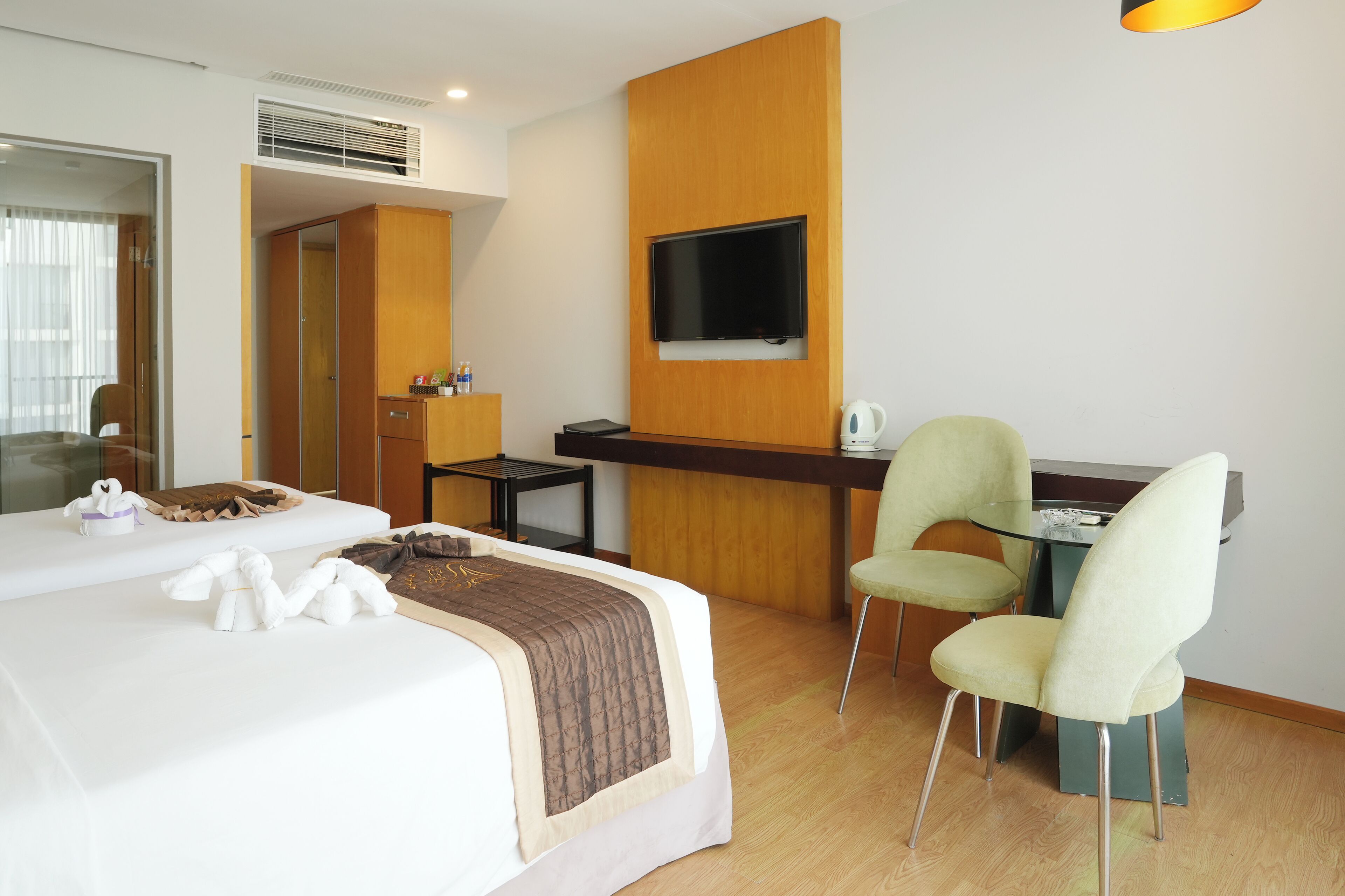 Una habitación de hotel con cama, escritorio, silla, televisor y espejo.