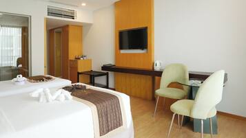 Una habitación de hotel con cama, escritorio, silla, televisor y espejo.