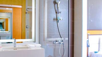 A modern bathroom with a glass shower enclosure, a white sink, and a mirror.