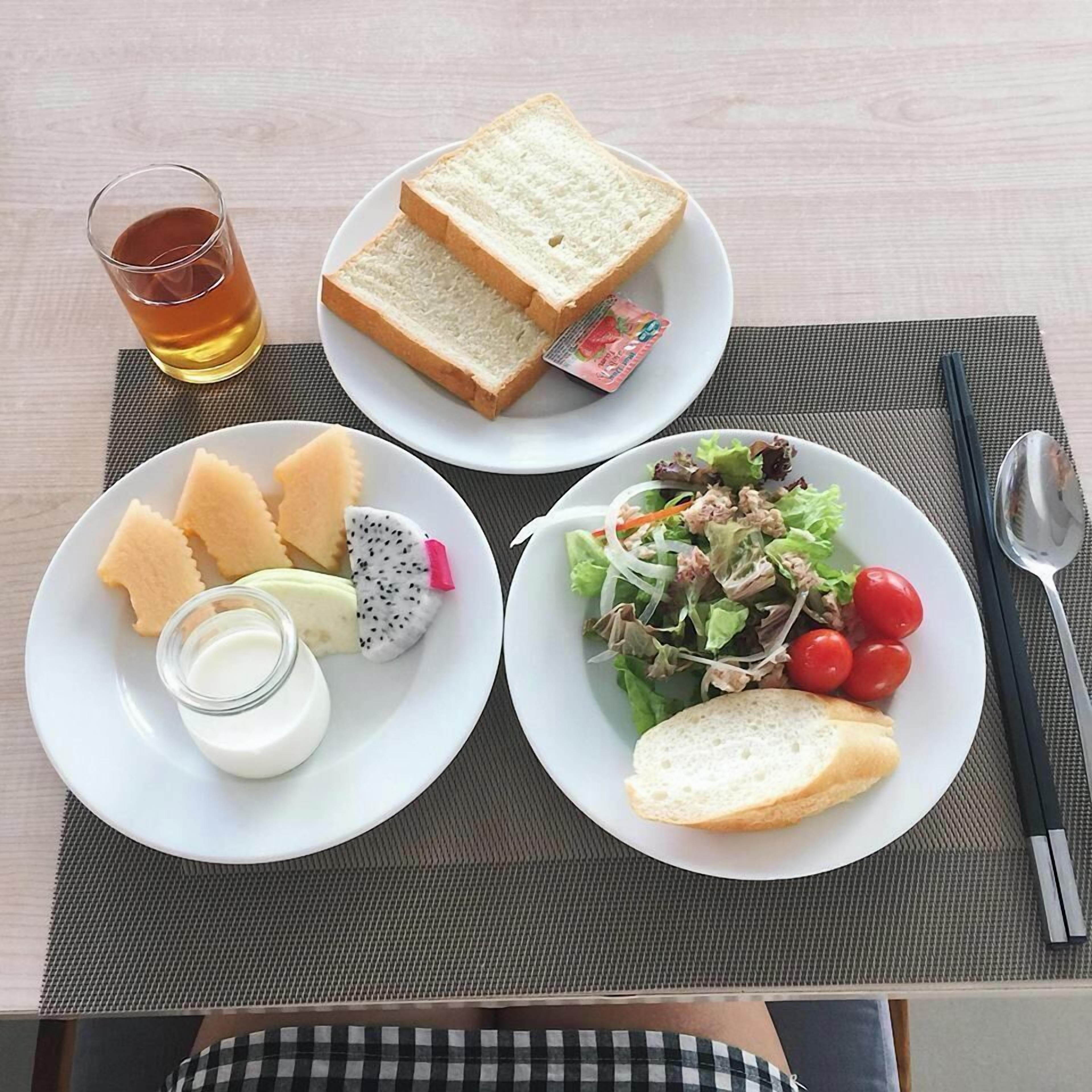 A table with a meal consisting of bread, salad, and a drink.