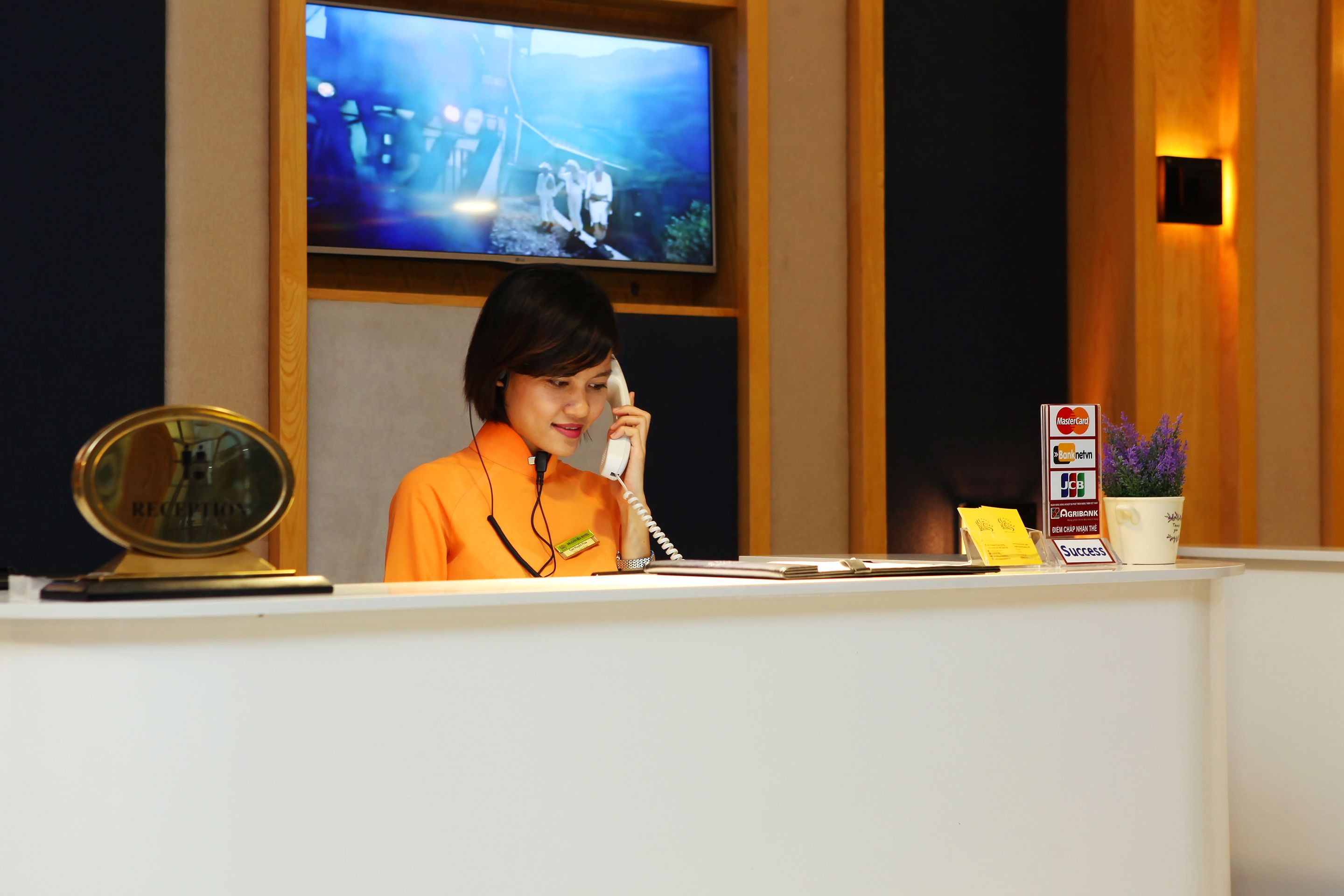 A reception desk with a television mounted above it displaying a scene.