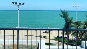 A view of the sea from a balcony with a railing, a street lamp, and a palm tree in the foreground. - Dragon Sea Sam Son Hotel (Sam Son)