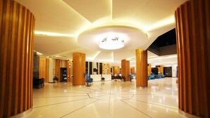 A spacious lobby with high ceilings, a central reception desk, and modern wooden accents. - Dragon Sea Sam Son Hotel (Sam Son)