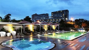 A rooftop pool area with lounge chairs and umbrellas, a hot tub, and a building in the background. - Dragon Sea Sam Son Hotel (Sam Son)