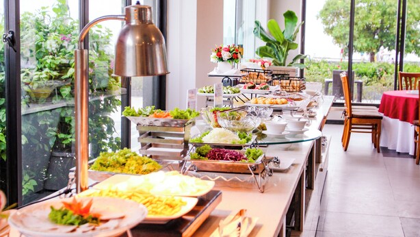 A buffet with various food items and a large window with a view of greenery. - Dragon Sea Sam Son Hotel (Sam Son)
