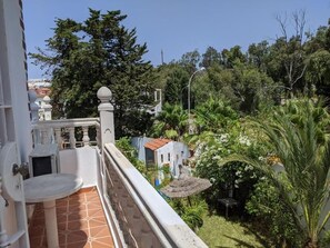 A balcony with a tiled floor, a small table, and a railing.