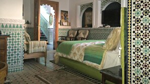 A traditional Moroccan-style bedroom with a bed, a chair, and a small table. - Malabata Guest House (Tangier)