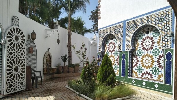 A courtyard with a tiled floor, decorative arches, and potted plants. - Malabata Guest House (Tangier)