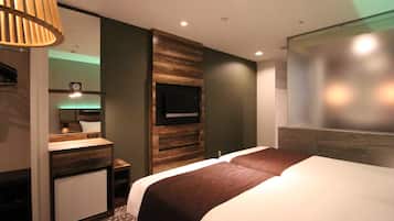 Une chambre d’hôtel moderne avec un grand lit, un téléviseur intégré, une petite kitchenette et un miroir.