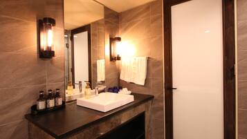 A modern bathroom with a large mirror, a white sink, and two wall-mounted lights.