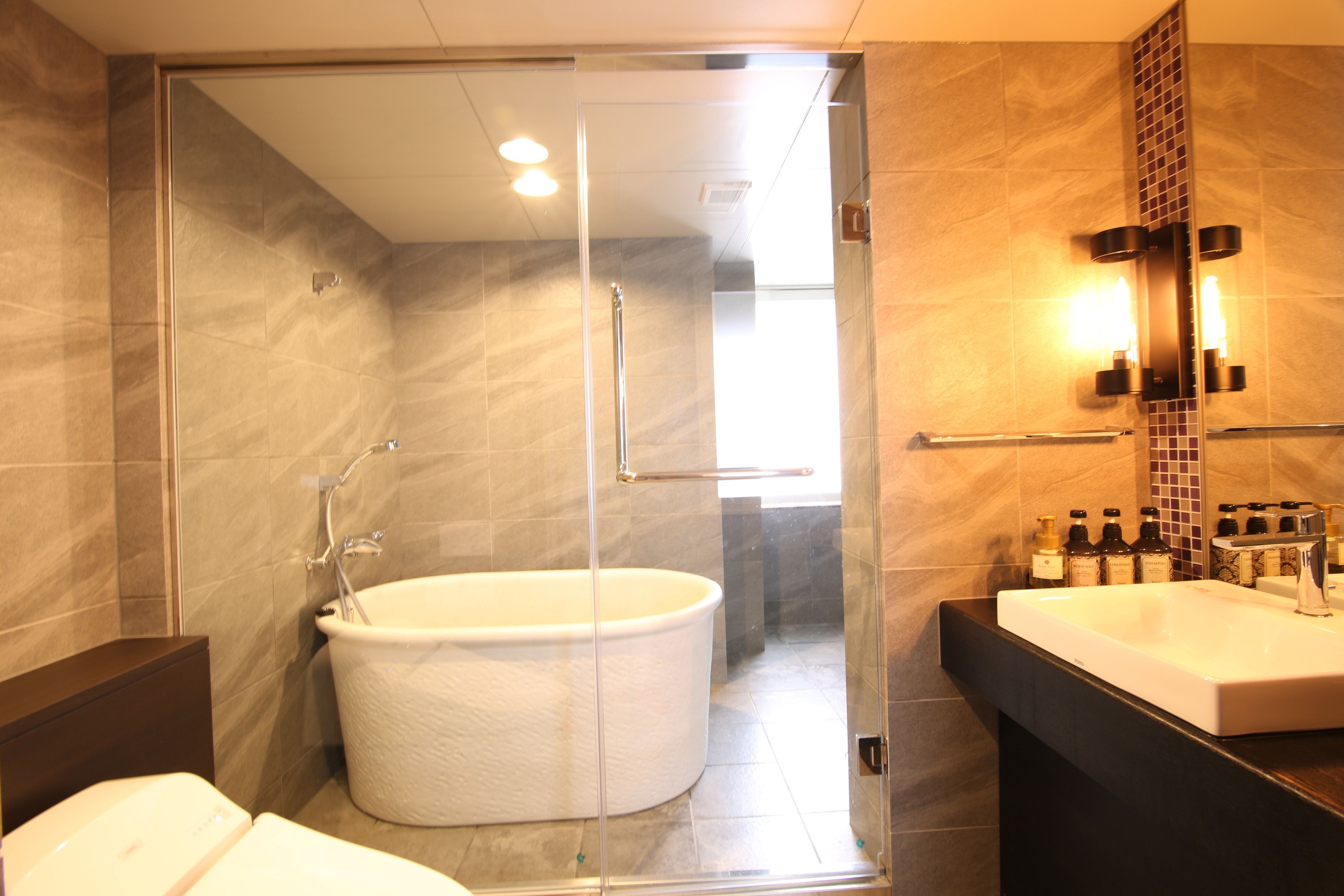 A modern bathroom with a glass-enclosed shower, a freestanding bathtub, and a vanity with a mirror and sink.