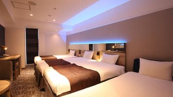 A hotel room with three beds, a desk, and a chair.