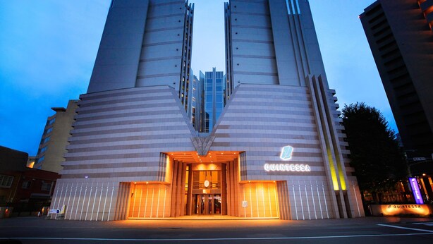 A hotel with a symmetrical facade, a central entrance, and the name 'QUINTESSA' illuminated on the building. - Quintessa Hotel Sapporo (Sapporo)