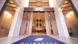 A hotel entrance with a blue carpet reading "QUINTESSA," large wooden doors, and a reception area with chairs and a counter. - Quintessa Hotel Sapporo (Sapporo)