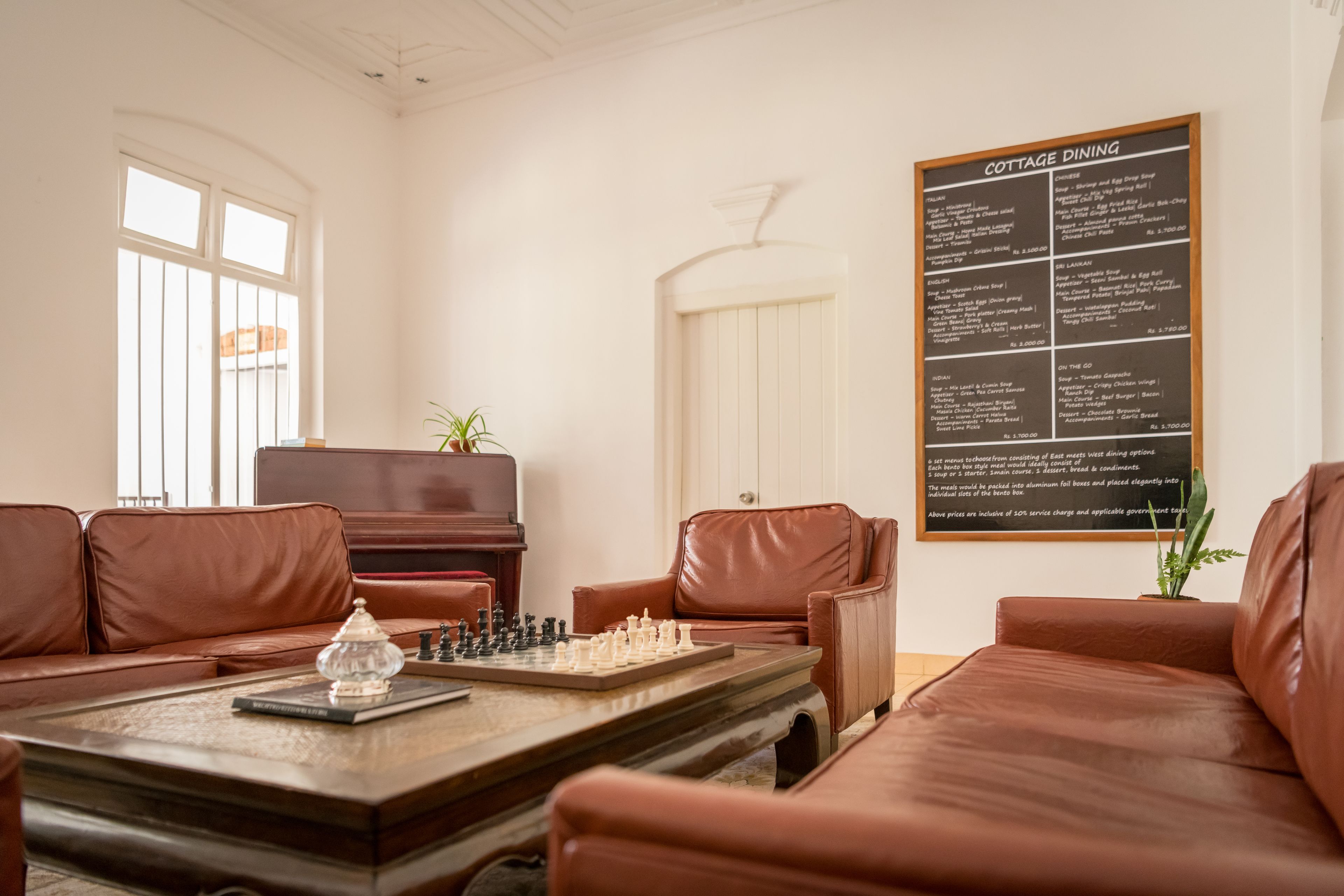 A cozy room with leather sofas, a wooden coffee table with a chessboard, and a menu on the wall.