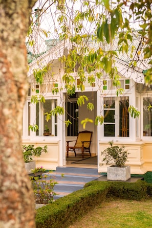 A traditional building with a covered porch, a wooden chair, and potted plants.