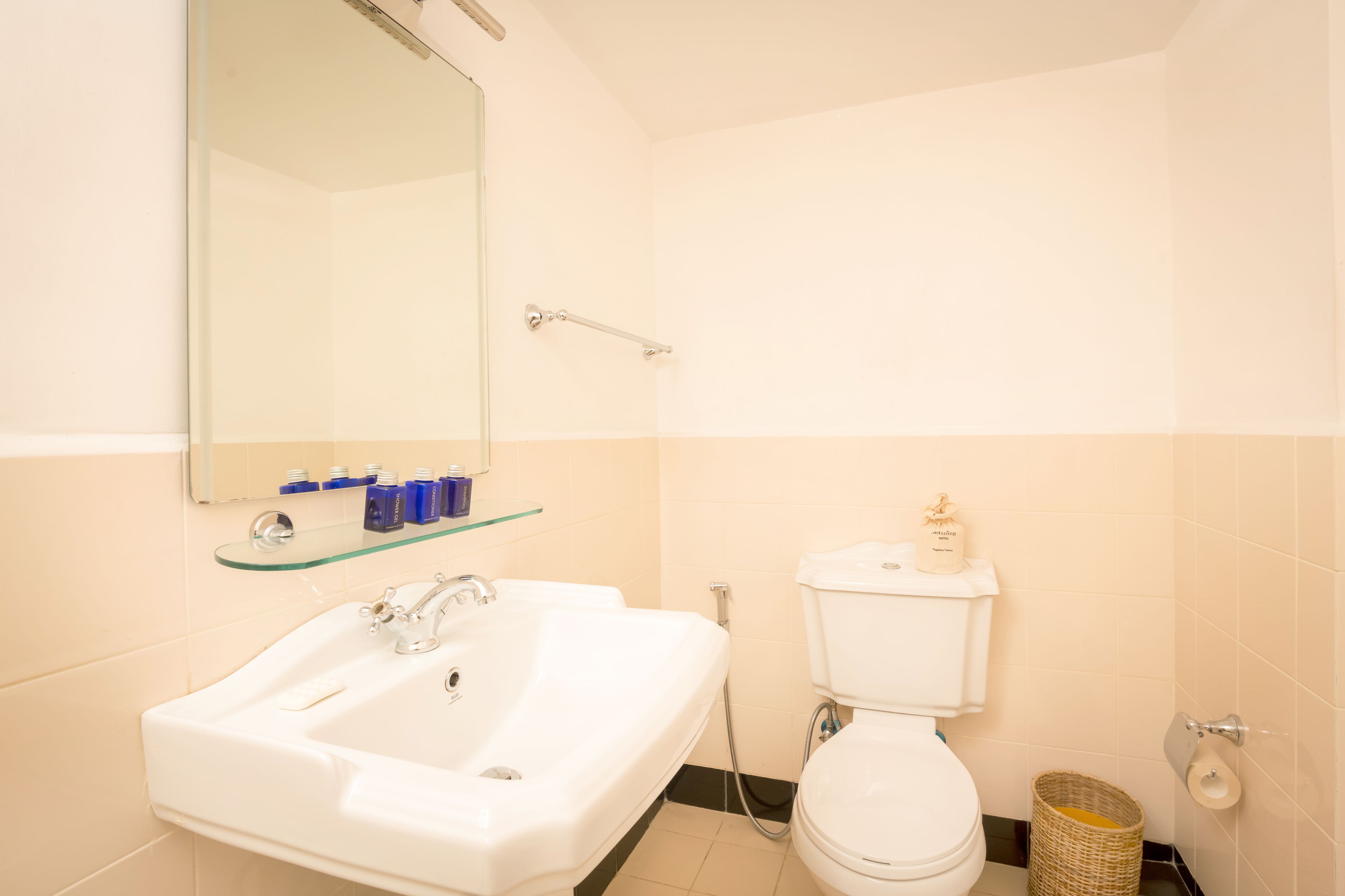 A bathroom with a white sink, mirror, and toilet.