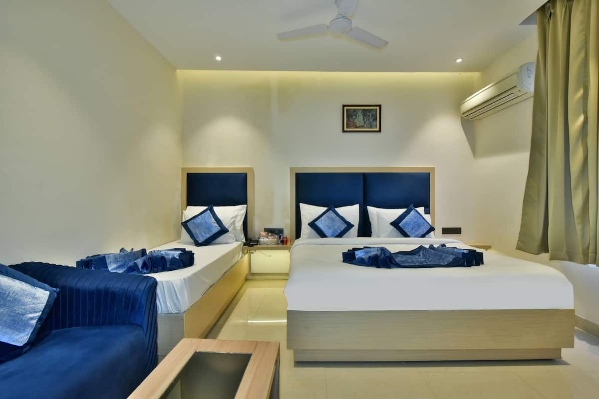 A hotel room with two beds, a ceiling fan, an air conditioning unit, and a small table.