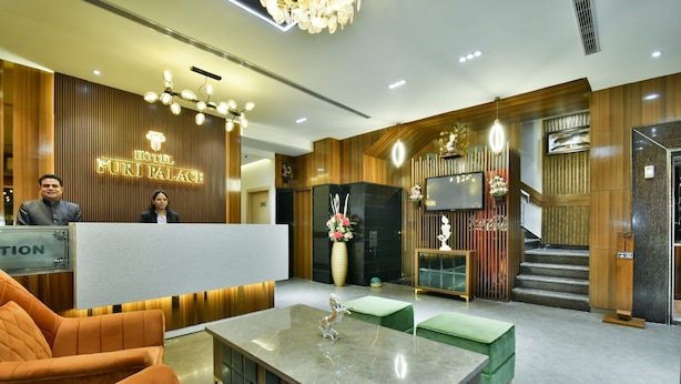 Zona de recepción de un hotel con un mostrador de madera, un televisor de pantalla plana y una escalera que lleva al piso superior.