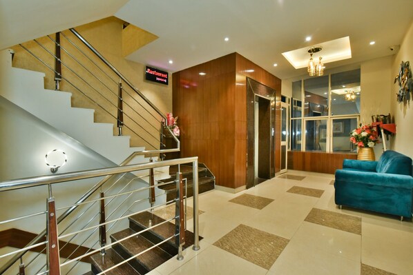 Un moderno vestíbulo de hotel con una escalera, una recepción y un sofá azul.