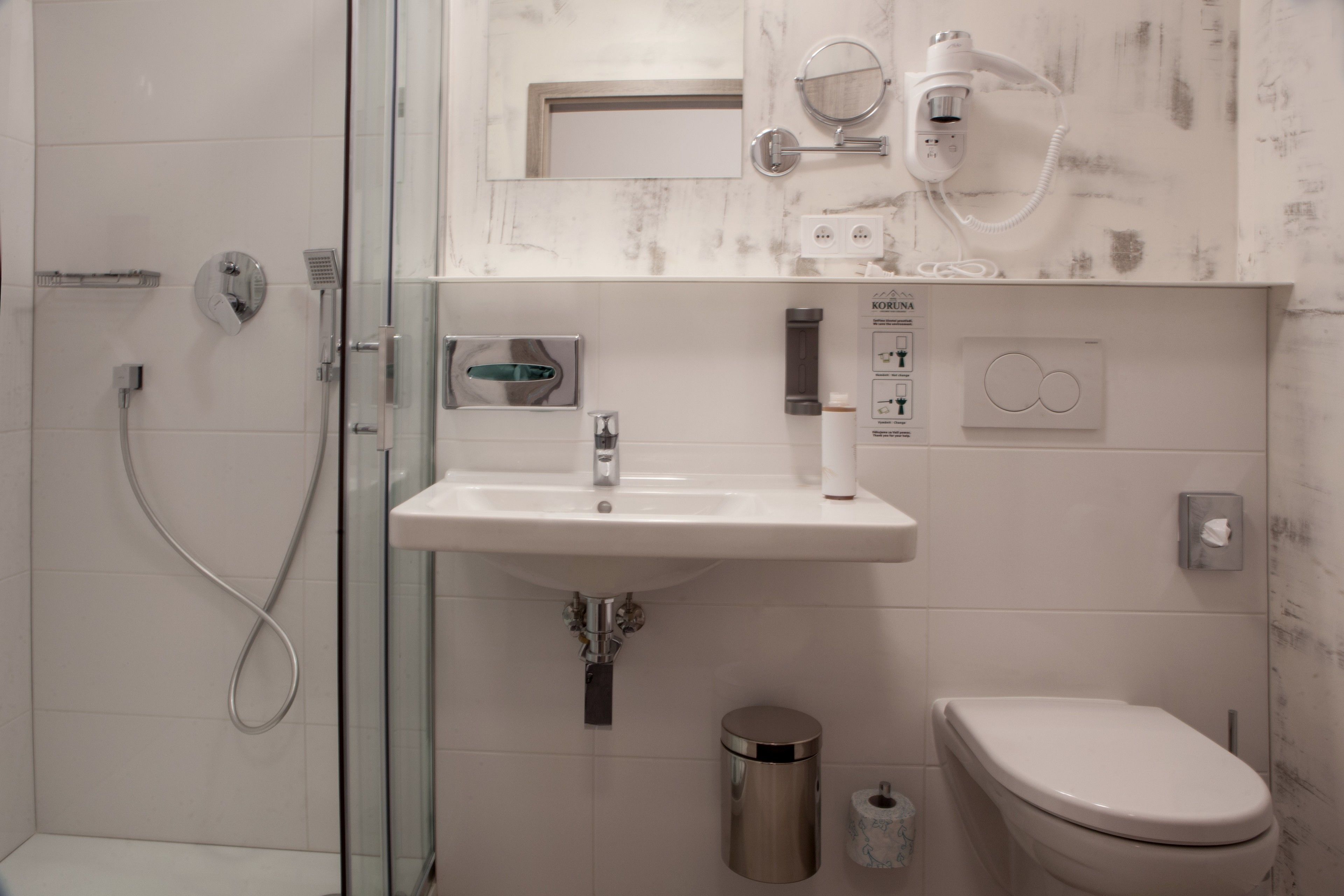 Ein modernes Badezimmer mit Duschkabine aus Glas, einem weißen Waschbecken und einer Toilette.