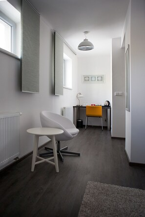 A modern, well-lit room with a desk, chair, and a small table. - Hotel Koruna (Chlumec nad Cidlinou)