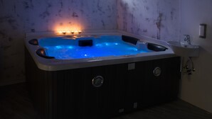 Una bañera de hidromasaje con iluminación azul, una ventana y un lavamanos.