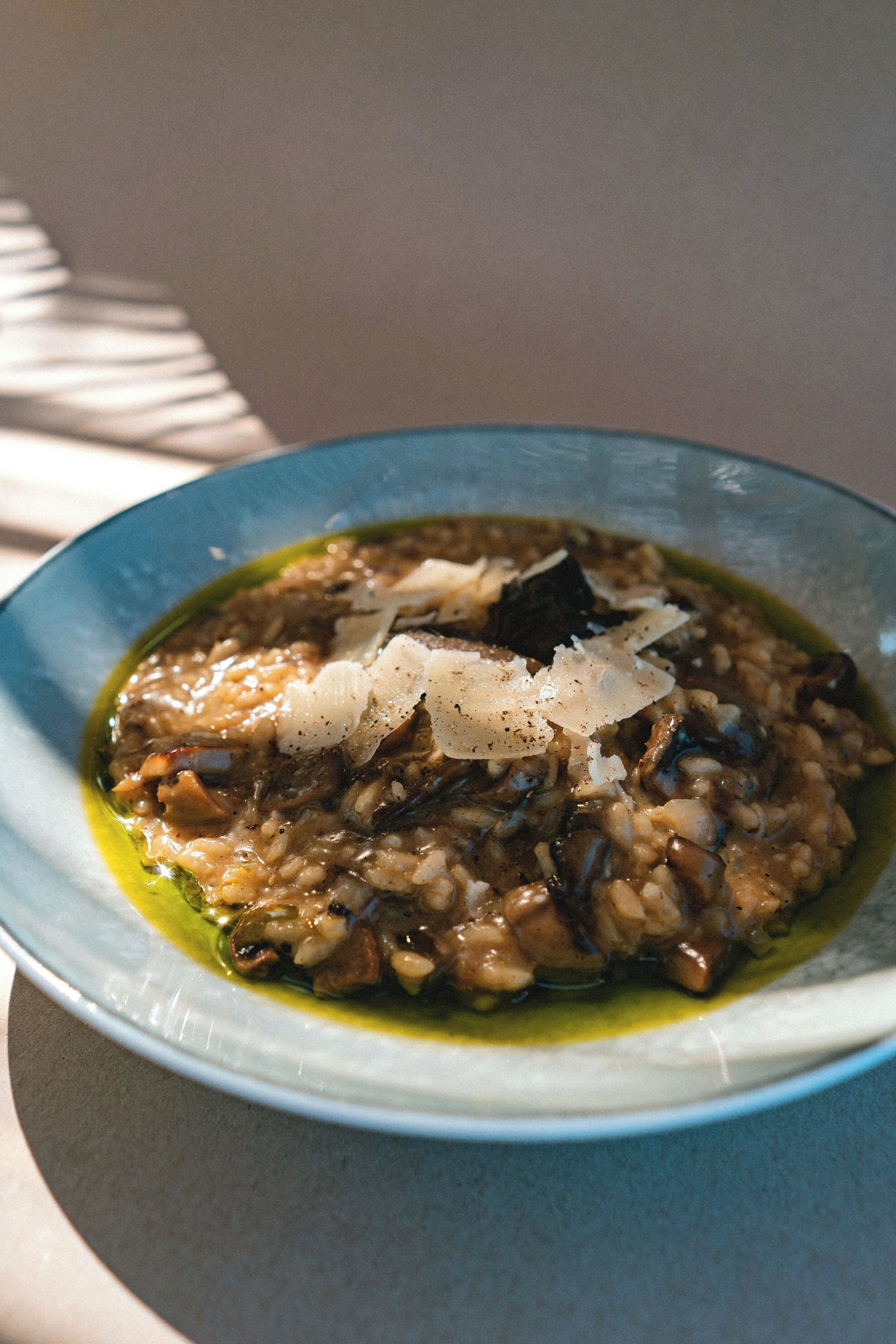 A bowl of risotto with mushrooms and grated cheese, served in a blue bowl.