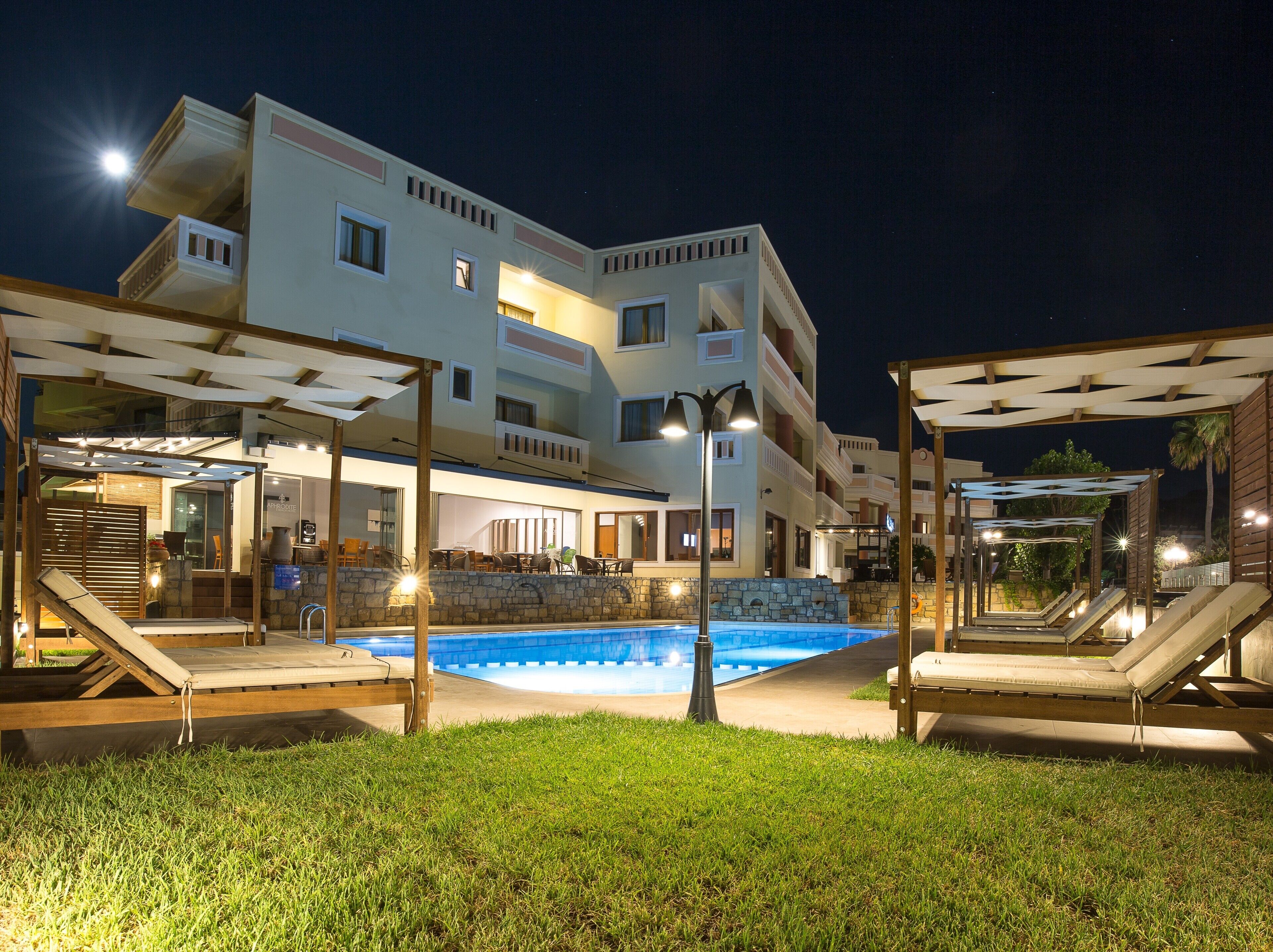 Un hôtel doté d’une piscine, d’un espace extérieur aménagé et d’une façade bien éclairée.
