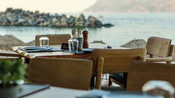 A table set for two with a view of the sea and rocks in the background.