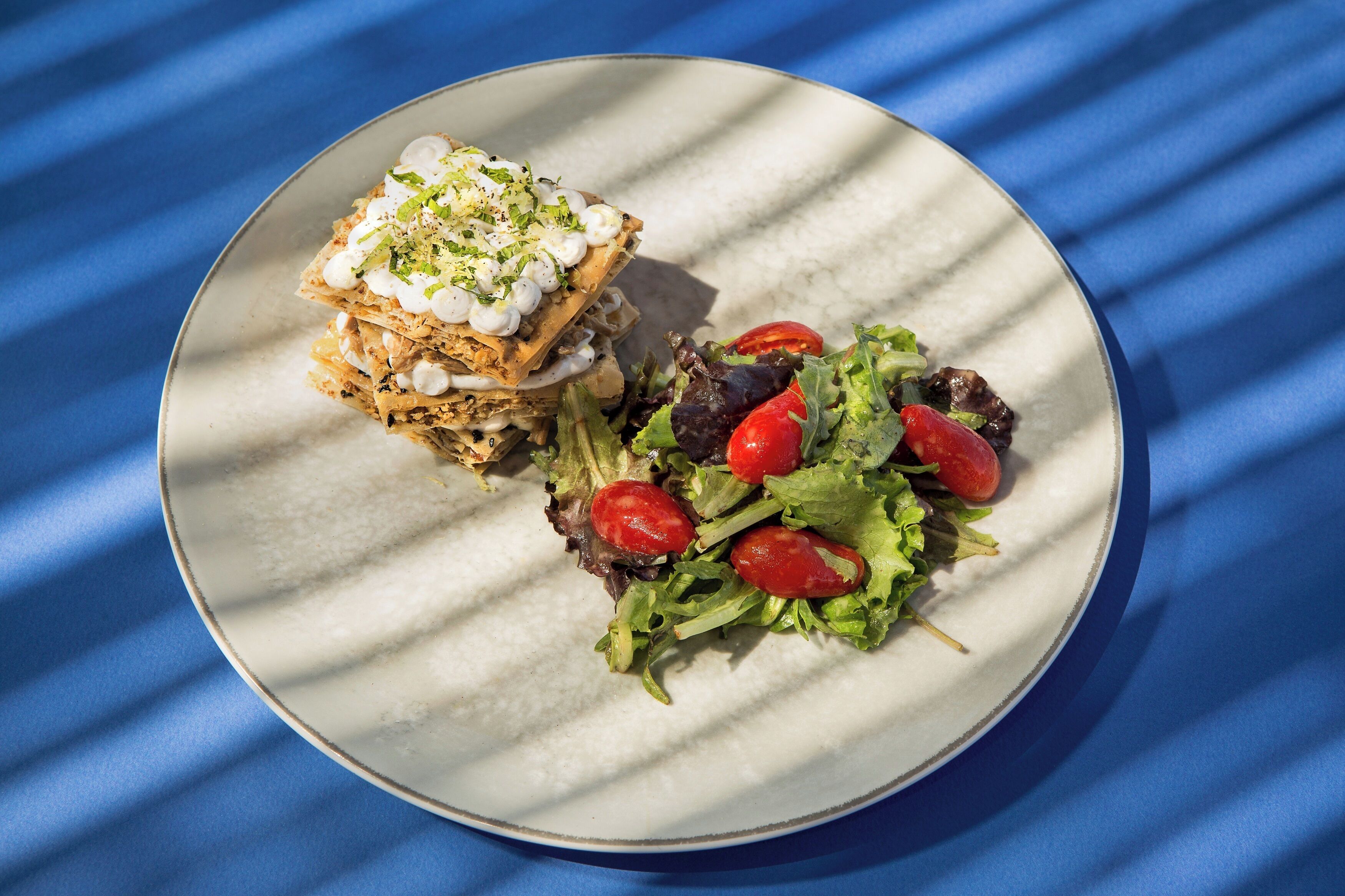 Un piatto con un'insalata e un piatto composto su un tavolo con tovaglia blu.