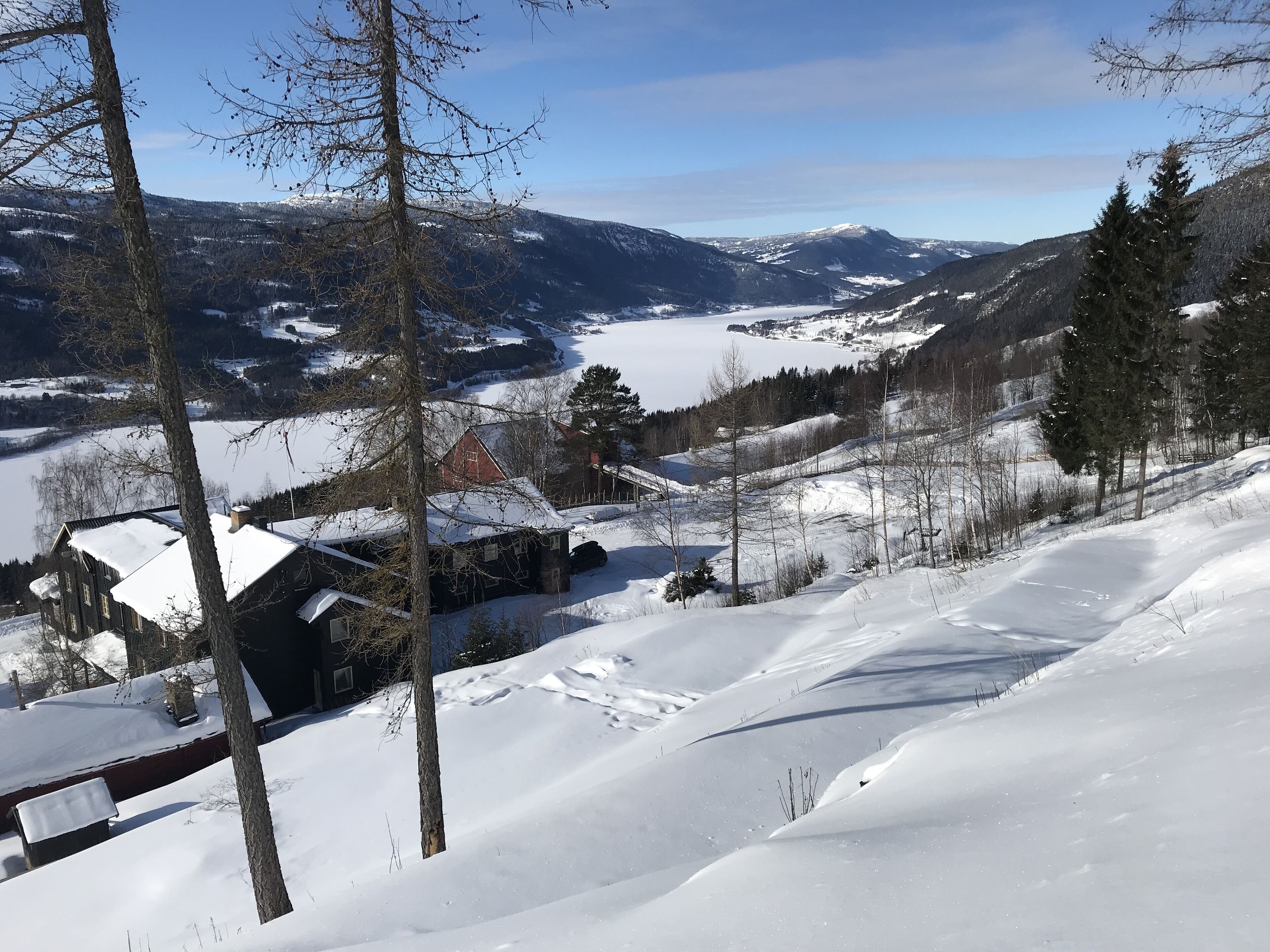 A snow-covered landscape with a house and a view of distant mountains.