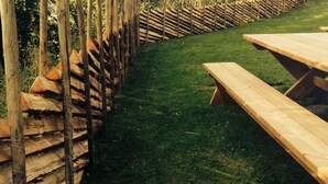A wooden fence with a slatted design, a grassy area, and a wooden picnic table. - Glomstad Gjestehus (Øyer)