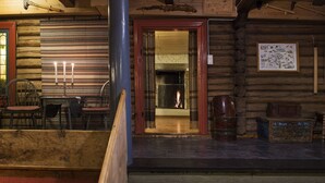 A log cabin interior with a fireplace, wooden walls, and a dining area with chairs and a table. - Glomstad Gjestehus (Øyer)