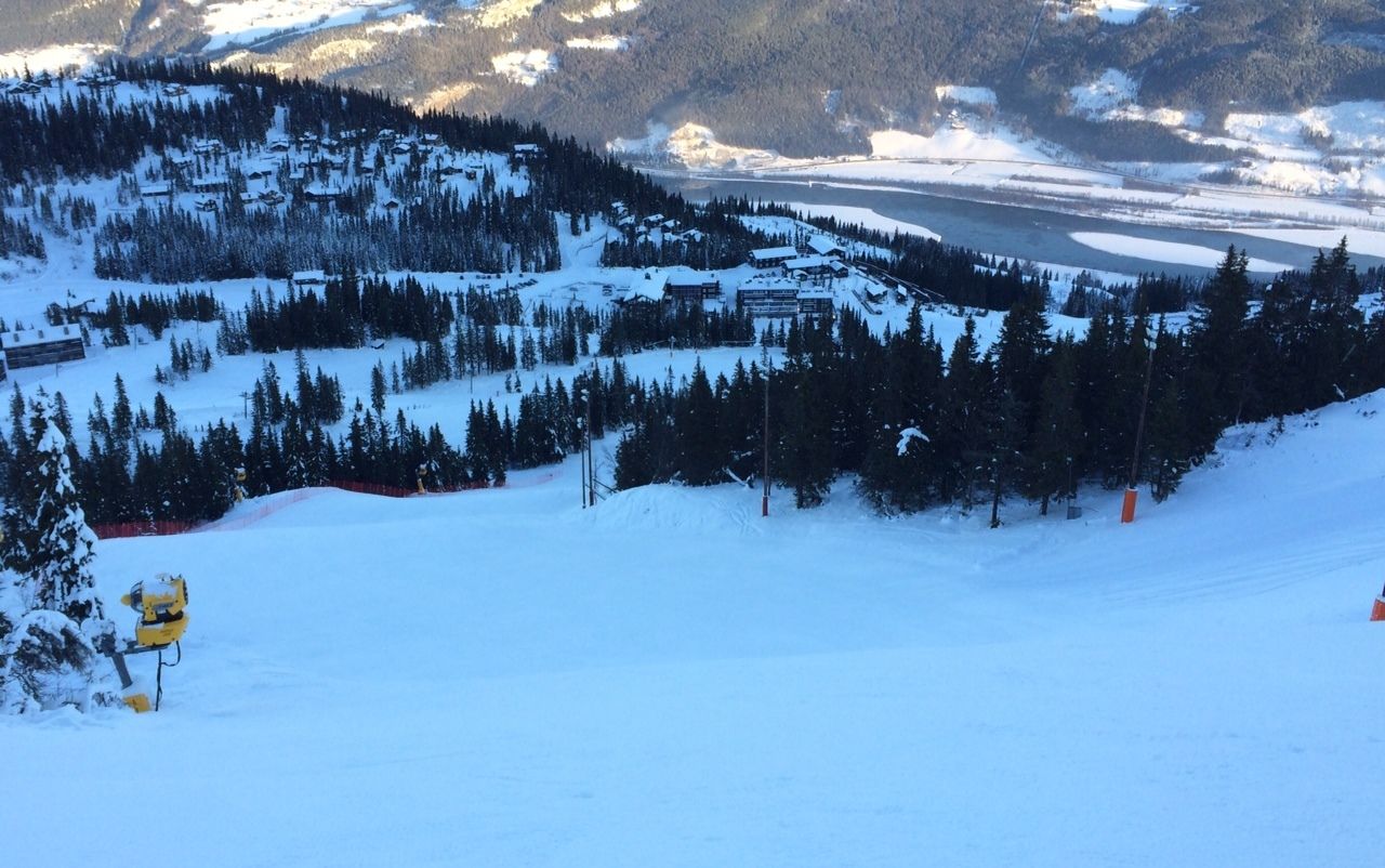 Une station de ski enneigée, avec une vue sur les montagnes, des remontées mécaniques et un lac.