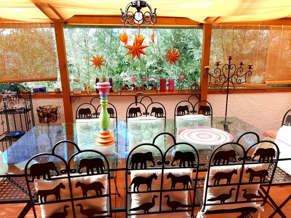 A covered outdoor seating area with tables and chairs, decorated with animal silhouettes and a colorful centerpiece.