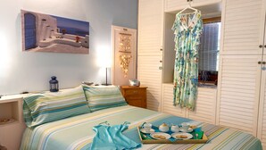 Un dormitorio con cama, mesita de noche, lámpara, ventana con cortinas y estante en la pared.