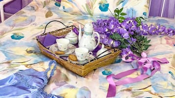 Ein Korbwäschetablett mit Tee-Service und Keksen auf einer blumigen Tischdecke.