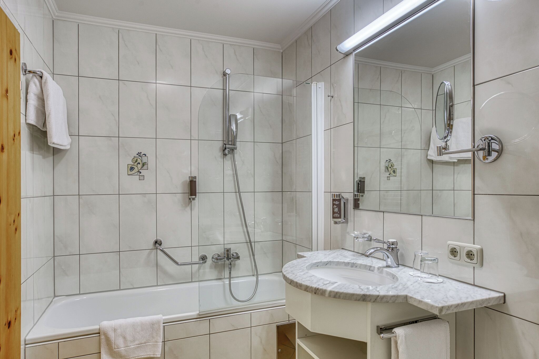 A modern bathroom with a bathtub, shower, and sink.