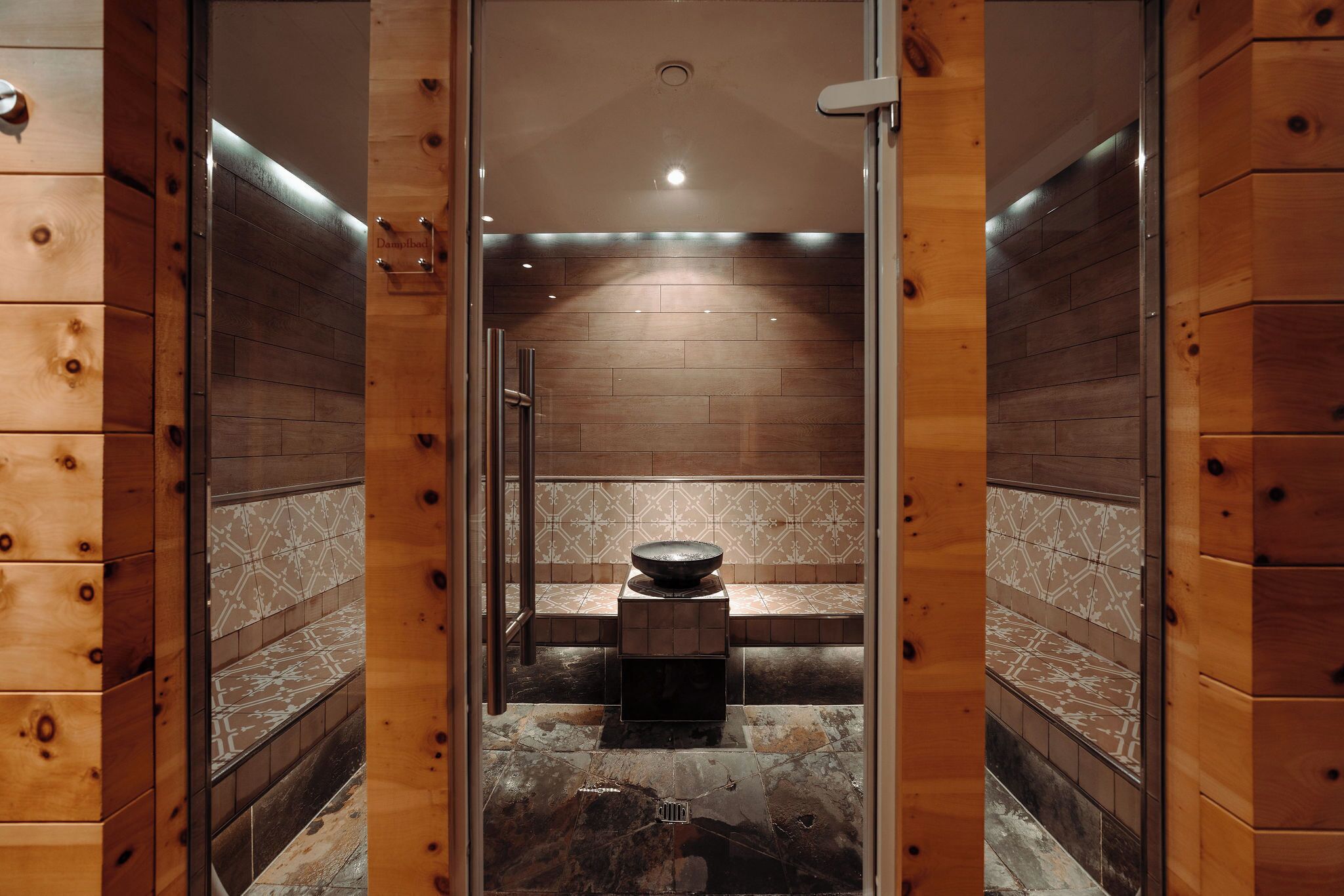 Ein Badezimmer mit Holzwänden, einem zentralen Waschbecken und gefliesten Wänden.
