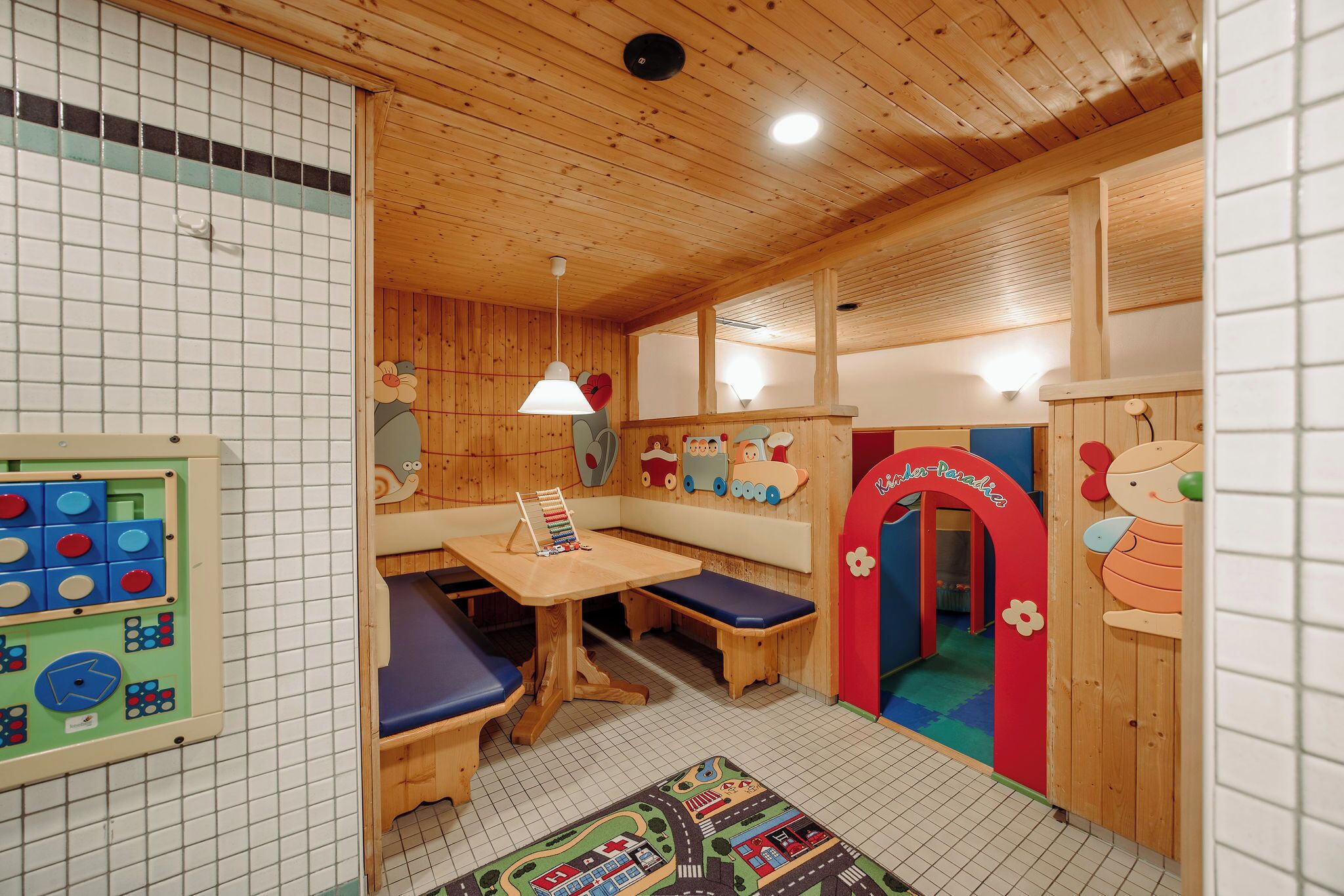 A children's playroom with wooden walls, a play table, and colorful decorations.