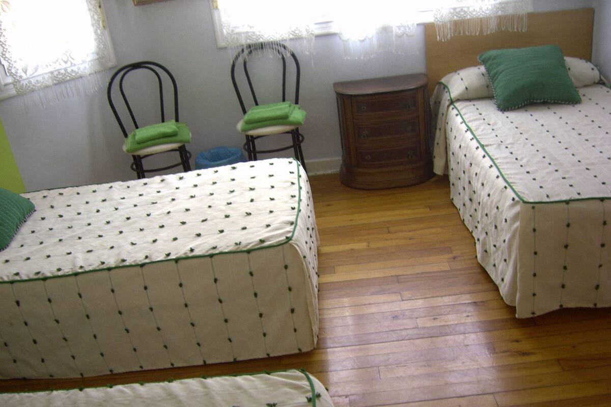 A room with two single beds, a wooden dresser, and two chairs.