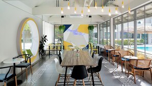 Een moderne eetruimte met een grote tafel, stoelen en hangende lampen.