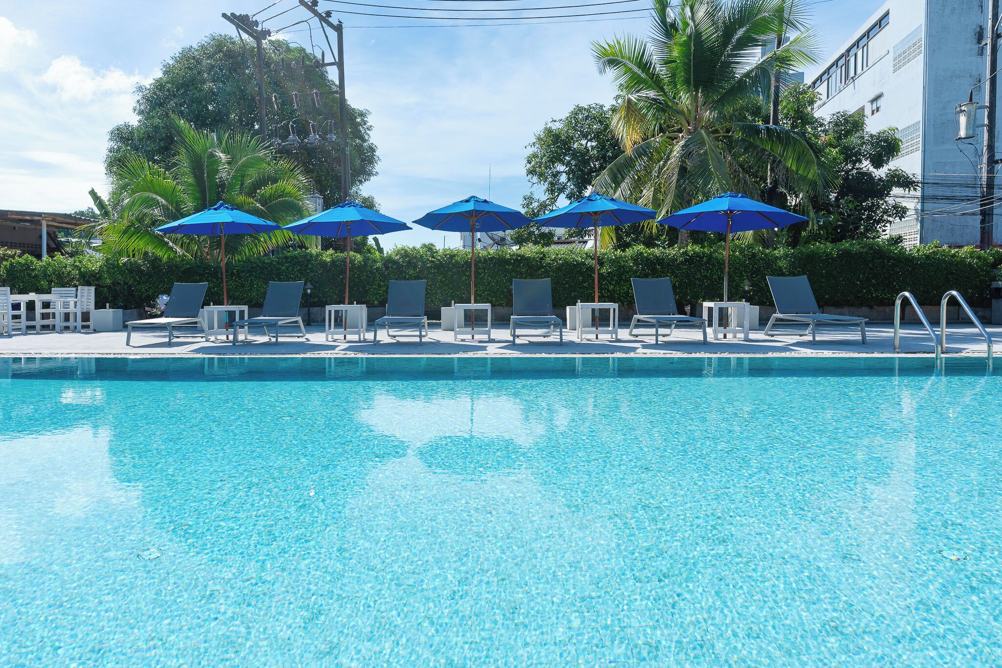 A clear blue pool with lounge chairs and blue umbrellas.