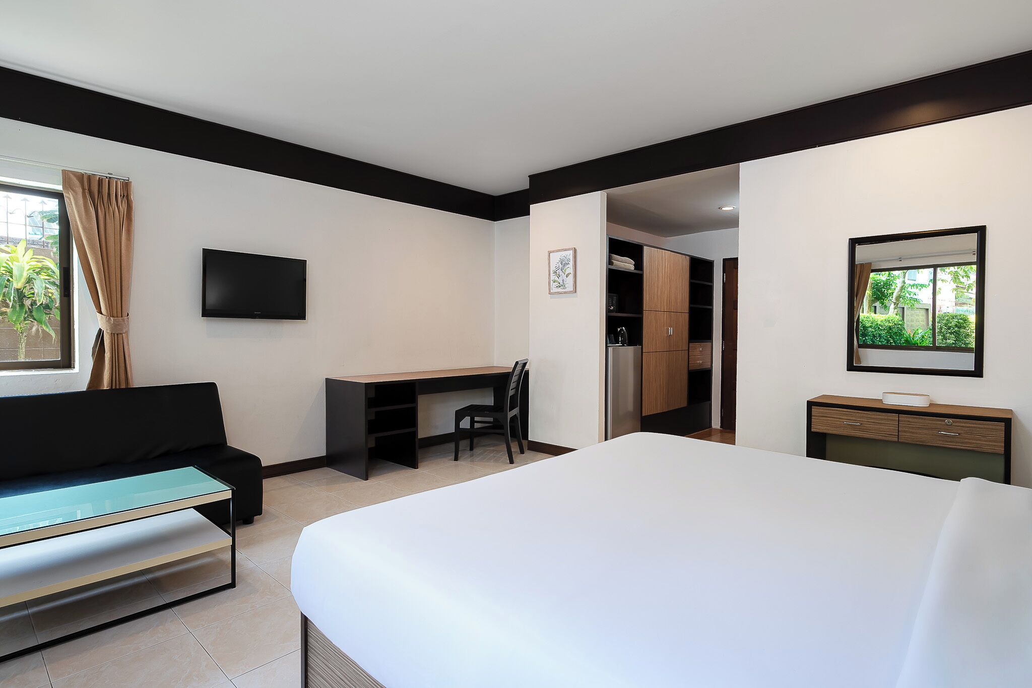 Une chambre d’hôtel équipée d’un lit, d’un bureau, d’une chaise, d’une télévision, d’une armoire et d’une fenêtre avec des rideaux.