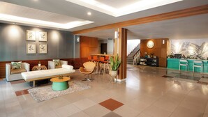 Een moderne lobby met een receptiebalie, een zithoek en een trap.