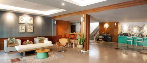 A modern lobby with a reception desk, seating area, and a staircase.
